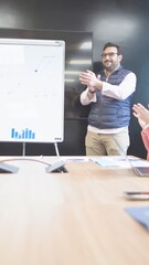 Man in vest applauding after a successful whiteboard presentation.