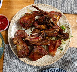 There is plate with cooked mutton barbecue shashlik on wooden table. Pieces of lamb fried on open...