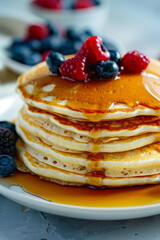 Stack of pancakes with maple syrup and berries