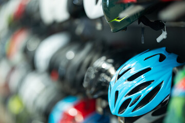 Bicycle helmets of different colors hang in row in sports store