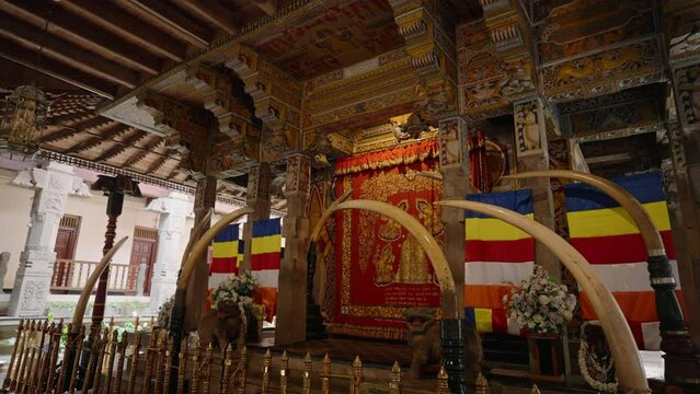 Interior of Sri Dalada Maligawa, Kandy. Sacred area with golden shrine, colorful flags. Worship space in Buddhist temple with intricate wood carvings, historical art. Religious tourism.