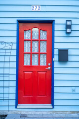 image of a closed colourful door- exterior image of wooden door- red and blue colourful entrance 