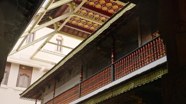 Rain drips from ancient temple roof at Sri Dalada Maligawa. Carved wood and intricate patterns adorn sacred site in Kandy. Serene atmosphere, cultural heritage on a wet day in slow motion. Slowmo