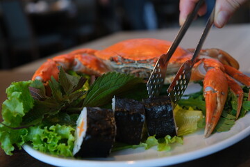 sushi with crab Steamed King crab in Japanese style in black bowl. Hand squeeze lemon with lemon juice drop.