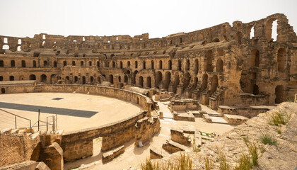 Scenic view of sun-drenched restored El Jem Amphitheatre arena encircled by ancient stone tiers and...
