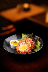 scotch egg with green salad and yellow mustard on plate on blurred background