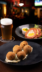 scotch egg with leafy salad with green fried meatloaf and yellow mustard on plate m blurred...