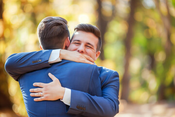 Obraz premium Handsome gay couple hugging in wedding suit enjoying the relationship with LGBTQ