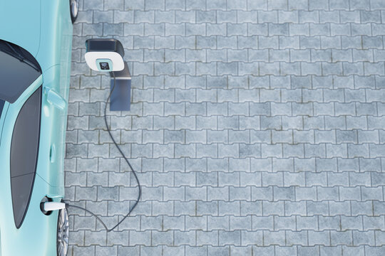 3d render of a nondescript Electric vehicle plugged into a Charging station on a parking lot with paving stones. Copy space - selective focus on the display of the charging station. Top down view