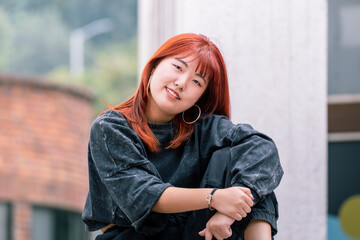 Korean dancer with red hair enjoys a relaxed moment during an outdoor break