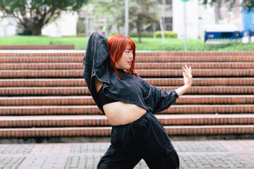 Young Korean woman in casual attire dancing on city stairs with enthusiasm