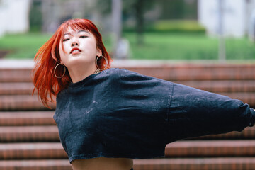 Korean woman with red hair lost in a flowing dance move on a city stairway