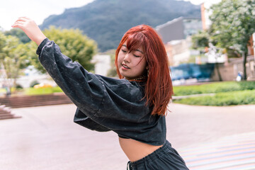 Spirited Korean woman with red hair dancing, framed by the cityscape, in a display of freedom and style