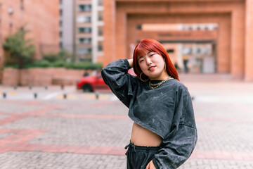 Confident Korean woman with striking red hair posing in a modern urban area