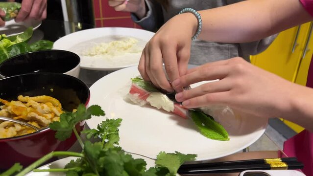 two women preparing spring rolls asian cuisine rolling vegetables meat fish in rice paper