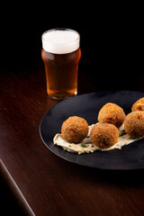 fried fish cake appetizer salmon cod with half pint of craft beer on wooden table