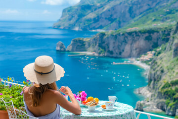 Young woman on summer vacation enjoying breakfast on a luxury hotel resort terrace overlooking the sea