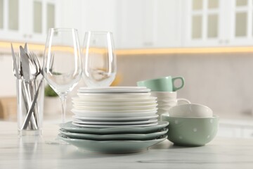 Many different clean dishware and glasses on white marble table in kitchen