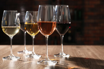 Different tasty wines in glasses on wooden table, space for text