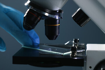 Scientist working with microscope on dark background, closeup