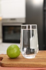 Filtered water in glass and lime on table in kitchen, closeup