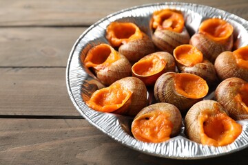 Delicious cooked snails on wooden table, closeup