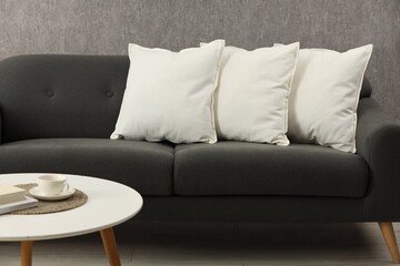 Soft white pillows on sofa and coffee table indoors