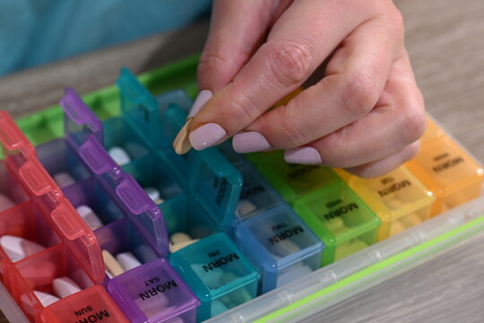 middle age hands load colorful monthly reminder pill box
