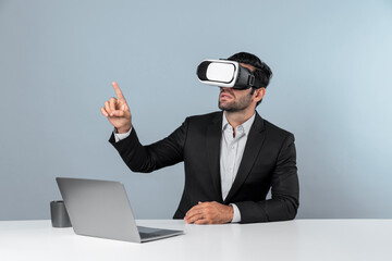 Skilled business man looking at data analysis while sitting at table with laptop and wearing VR glasses. Project manager working by using virtual reality system or connecting at metaverse. Deviation.