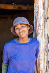 african village, single teenager girl in front of the door outdoors , mud hut interior dirty walls