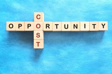 Opportunity cost in economics concept. Crossword puzzle flat lay in blue background.
