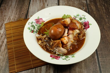 Local crispy pork and boiled egg topping on cooked rice and dressing with gravy sauce. Famous street food menu in Chinese restaurant.