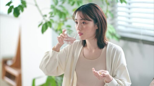 ベッドでサプリを飲む20代女性