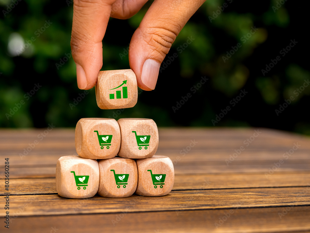 Poster growth graph icon block in hand put on top of wood pyramid cube blocks with green shopping cart symb