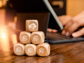 Cloud computing technology management concept. Cloud symbol and digital document file icons on wooden cube blocks pyramid stack near businessman work with tablet computer. Protection and security.