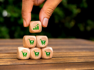 Growth graph icon block in hand put on top of wood pyramid cube blocks with green shopping cart...