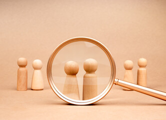 Human resource (HR), hiring, couple, partner selection, recruitment, love calculator match, online dating concepts. Male and female wooden figures were chosen in magnifying lens on beige background.