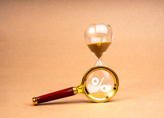 Tax time deadline concept. Percentage icon in magnifying glass lens on hourglass, isolated on brown recycled paper background, minimal style. Interest Rate Swap (IRS), Time limit for annual taxation.
