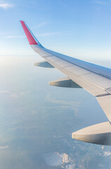Fototapeta premium View from the airplane window at a beautiful cloudy sky and the airplane wing
