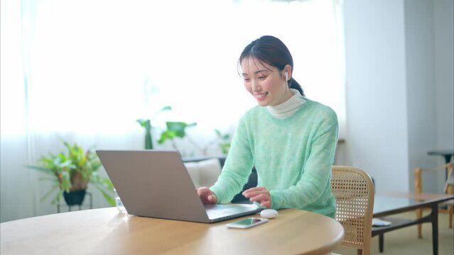 リビングでオンラインミーティングをする20代女性
