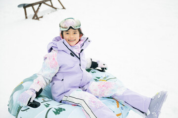 雪山でそりをする小学生の女の子