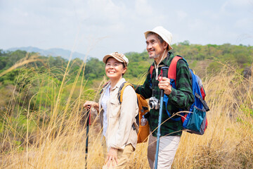 active asian senior couple hiking on the mountain,both of them stop stop walking for a moment,look freedom emotion,successful and smile,concept of elderly retired activity,travel,adventure in nature