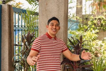 A cheerful middle-aged Asian man caught aback, with hands raised and a bright smile.