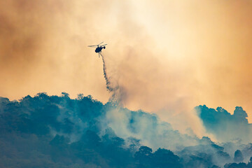 Fire fighting helicopter carry water bucket to extinguish the forest fire.