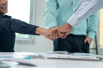 Three people are shaking hands in a business meeting. Scene is professional and friendly