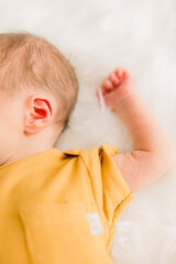 An adorable newborn baby sleeping. Close-up of the baby's ear and arm and tiny hands curled up
