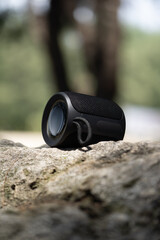 Small portable wireless bluetooth speaker on the background of nature. Listening to music in...