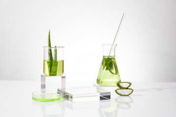 Laboratory layout in white tones, blank rectangular pedestal placed in center, decorated by some aloe vera and lab items filled by transparent fluid. Front view photo with blank space