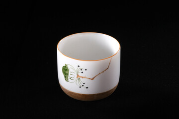 A beautifully printed white ceramic tea cup on a black background