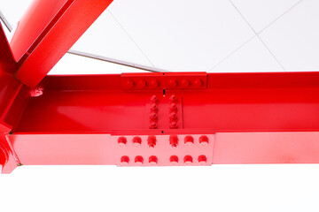 Large red screw hexagon flange nut supporting structures, metal frame of prefabricated building on white background. Large metal posts or structure are painted of outdoor billboard construction work.	